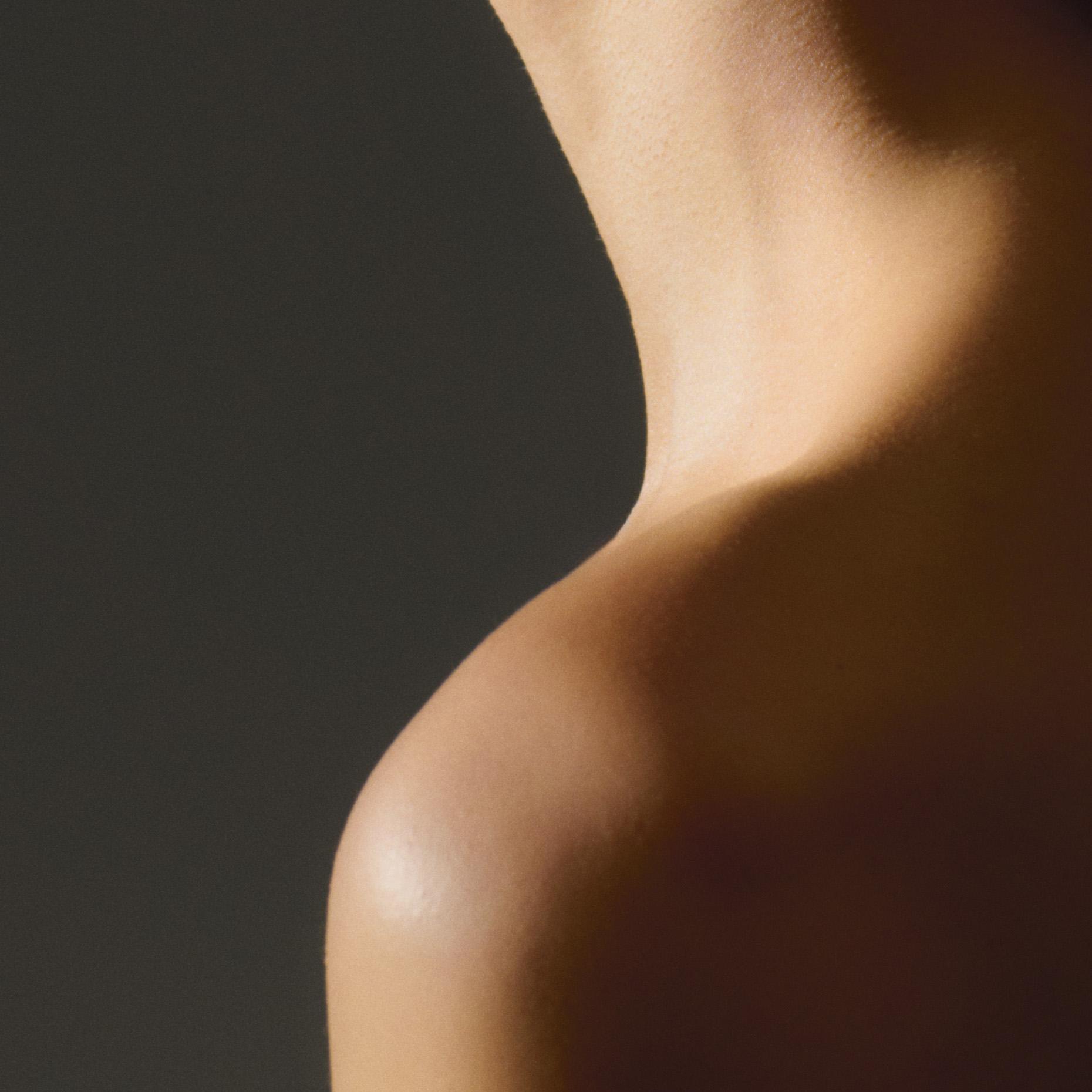 Close-up of a person's shoulder and neck, with light and shadow creating a dramatic effect.